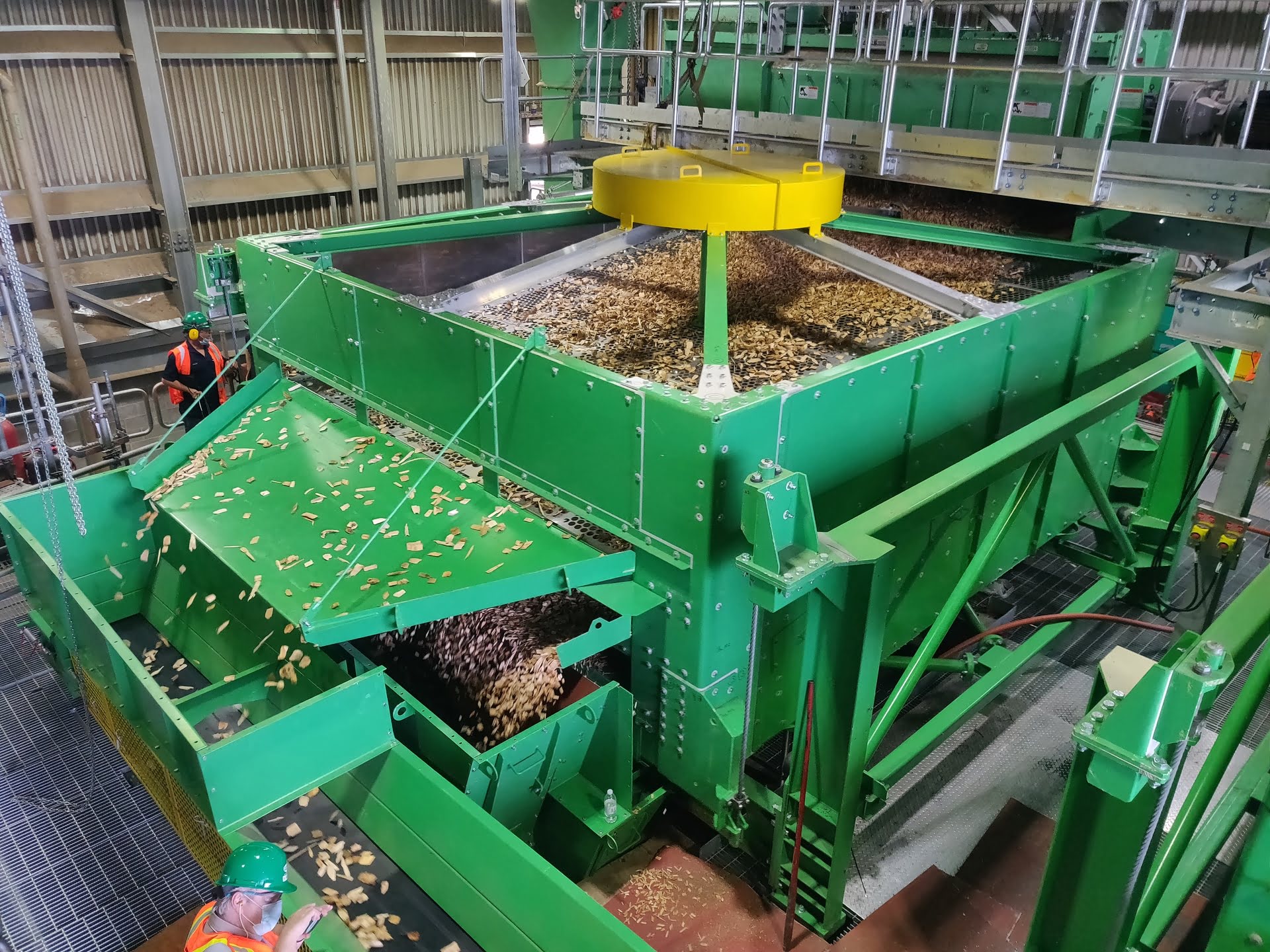 view on a chip screening system with several wood chips, oversized chips are sorted out an accept are further transported